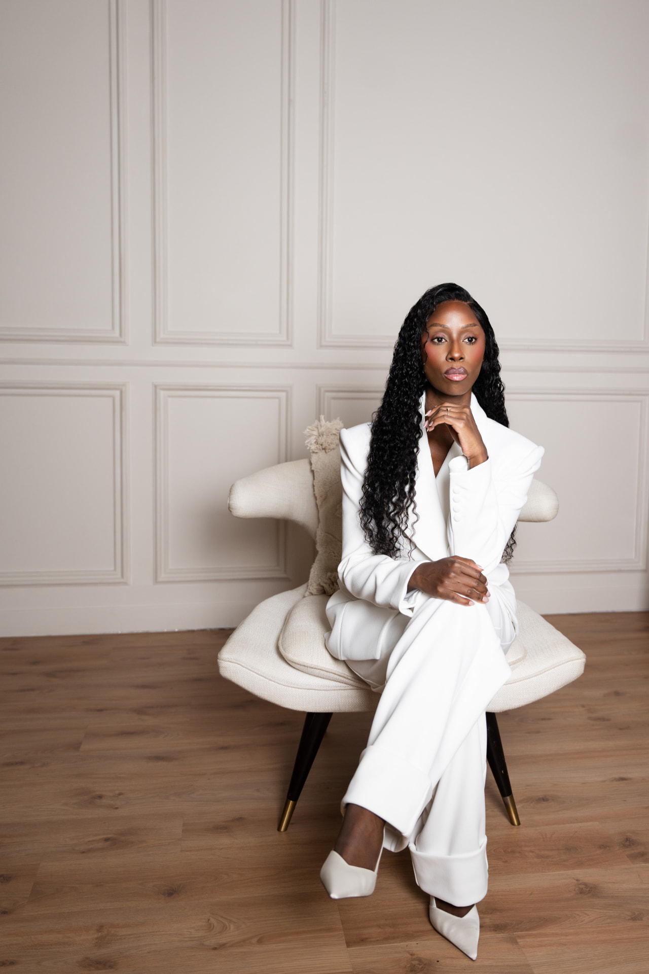 Nyambura Marincowitz, RTT® therapist, seated in a white suit in a softly lit room